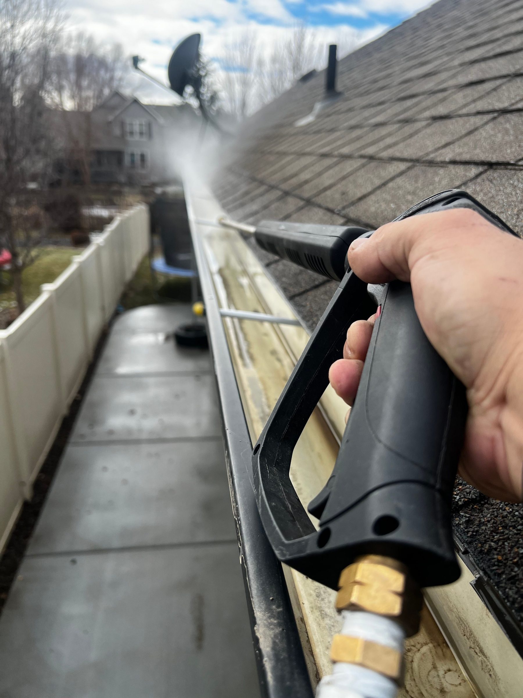 Technician pressure cleaning gutters on residential home