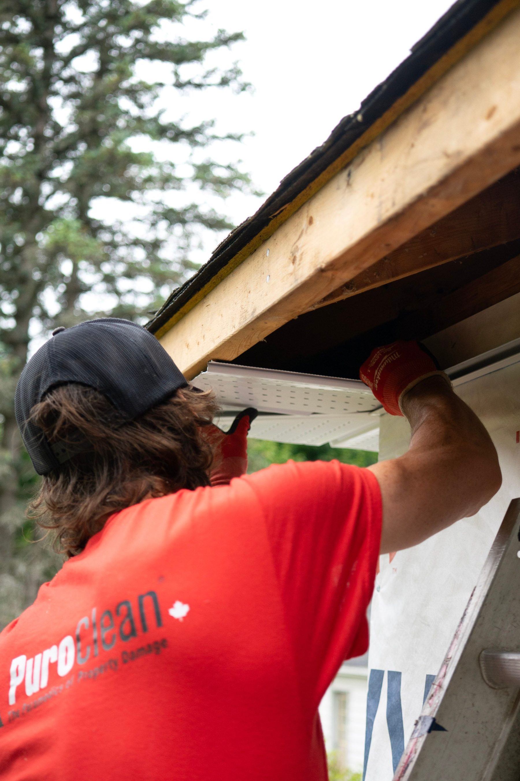Professional clearing debris from roof gutter