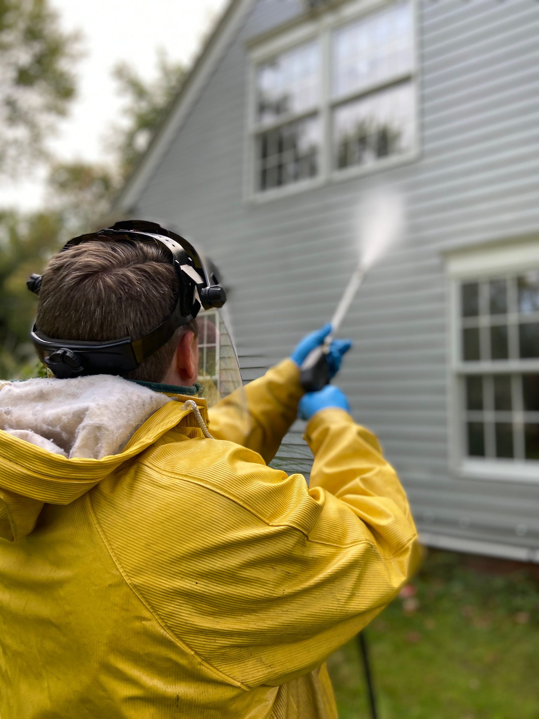 Technician pressure washing house siding